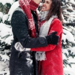 Couple enjoying a loving embrace in a snowy forest, exuding warmth and happiness.